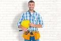 Composite image of smiling handyman holding hardhat and hammer Royalty Free Stock Photo