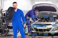 Composite image of smiling male mechanic holding tire Royalty Free Stock Photo