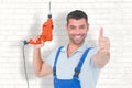 Composite image of smiling repairman with drill machine gesturing thumbs up Royalty Free Stock Photo