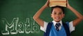 Composite image of smiling schoolboy carrying books on head over white background Royalty Free Stock Photo