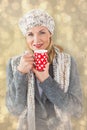 Composite image of smiling woman in winter fashion looking at camera with mug Royalty Free Stock Photo