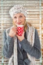 Composite image of smiling woman in winter fashion looking at camera with mug Royalty Free Stock Photo