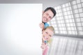 Composite image of smiling young couple hiding behind a blank sign Royalty Free Stock Photo