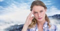 Composite image of stressed caucasian woman against blue sky over winter landscape