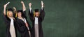 Composite image of three students in graduate robe raising their arms