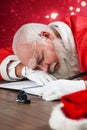 Composite image of tired santa claus napping at desk while writing a letter with a quill Royalty Free Stock Photo