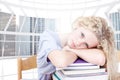 Composite image of tired teeenager sleeping in a library Royalty Free Stock Photo