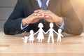 Composite image of underwriter protecting family in paper with his hands Royalty Free Stock Photo
