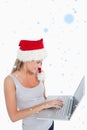 Composite image of woman with a christmas hat using a laptop Royalty Free Stock Photo