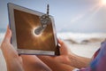 Composite image of woman sitting on beach in deck chair using tablet pc Royalty Free Stock Photo