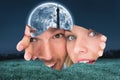 Composite image of young couple peeking through torn paper Royalty Free Stock Photo