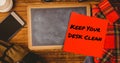 Composite of keep your desk clean on sticky note with slate, cellphone with t-shirt on table Royalty Free Stock Photo