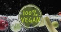 Composite of 100 percent vegan text over fresh fruit in water with copy space