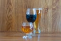 Composition of alcoholic drinks with glass of whiskey, glass of clear beer and glass of red wine on stage of oak tables