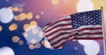 Composition of american flag billowing over defocussed bokeh orange and white lights on sunset sky Royalty Free Stock Photo