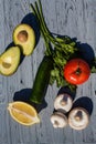 Composition of an appetizing half of an avocado, tomato, cucumber, raw champignons, lemon and parsley