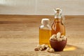 Aromatic oil in a glass jar and bottle with pistacios in bowl on wooden table, close-up.