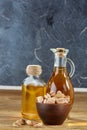 Aromatic oil in a glass jar and bottle with pistacios in bowl on wooden table, close-up.