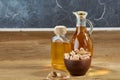 Aromatic oil in a glass jar and bottle with pistacios in bowl on wooden table, close-up.