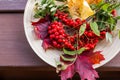 Composition of autumn berries, leaves and fruits on wooden background. Red Rowan berries and colorful autumn leaves