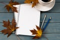 Composition with autumn leaves, blank notebooks, a cup of coffee on a blue wooden table Royalty Free Stock Photo