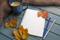 Composition with autumn leaves, blank notebooks, a cup of coffee on a blue wooden table Royalty Free Stock Photo