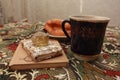 Composition of banana puff on a plate, a blue cup of tea, a fork, two notebooks and a citrine stone on a multi-colored tablecloth. Royalty Free Stock Photo