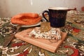 Composition of banana puff on a plate, a blue cup of tea, a fork, two notebooks and a citrine stone on a multi-colored tablecloth. Royalty Free Stock Photo