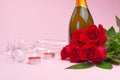 A composition of a beautiful bouquet of roses, candles, glasses and a bottle of champagne creates a romantic card. The concept of Royalty Free Stock Photo