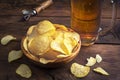 Glass of beer, potato chips in a bowl on a dark wooden background. Pouring light beer in a glass. Royalty Free Stock Photo