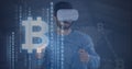 Composition of binary coding bitcoin symbols over man wearing vr headset touching screen