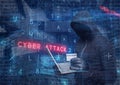 Composition of binary coding and cyber attack warning text over hacker in hood using laptop Royalty Free Stock Photo