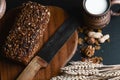 Composition black bread on the board, vintage knife, milk, wheat flakes, nuts on the table and the old background, concept of heal Royalty Free Stock Photo