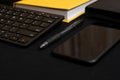 Composition with black pen, computer keyboard, smartphone, leather wallet and bright yellow notebook on dark black surface. Royalty Free Stock Photo