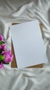 Composition with a blank paper and pink flowers on white piece of cloth Royalty Free Stock Photo