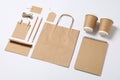 Composition with blank stationery, paper cups and bag on white background