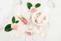 composition with a bottle of rose essential oil, buds and flower leaves, mortar and pestle and rose petals. marble white Royalty Free Stock Photo