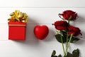 Composition from a bouquet of beautiful red roses and a gift jewelry box on the background. Royalty Free Stock Photo