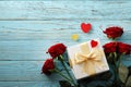 Composition of a bouquet of red roses, gift box on a blue wooden background, Valentine`s Day. Royalty Free Stock Photo