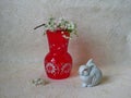 Composition: a branch of blooming cherry on a red vase and a rabbit figurine Royalty Free Stock Photo