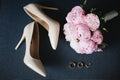 Composition from the bridal bouquet of beautiful pink peonies flowers with a pair of modish bridal shoes and wedding Royalty Free Stock Photo