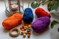 Composition in bright colors of yarn, beads, pins and knitting needles. Nearby is a candle in a metal candlestick and green leaves