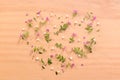 Composition of a bunch of small purple flowers on a wooden table forming a heart