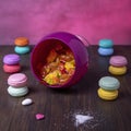 Composition of candies in an overturned glass container and pairs of superimposed colorful macarons