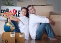 Composition of cardboard boxes with globe and couple in new home with sold sign Royalty Free Stock Photo