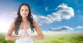 Composition of caucasian woman meditating with eyes closed with copy space over clouds and blue sky Royalty Free Stock Photo