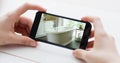 Composition of caucasian woman's hands holding smartphone with photo of bathroom