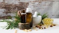 composition of cedar oil with pine nuts on a background of a branch with a pine cone, on a light wooden background