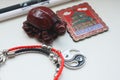 A composition of a Chinese red tortoise figurine, a black and white pen, a bracelet with a yin yang symbol and a metal magnet.
