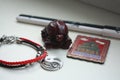 A composition of a Chinese red tortoise figurine, a black and white pen, a bracelet with a yin yang symbol and a metal magnet.